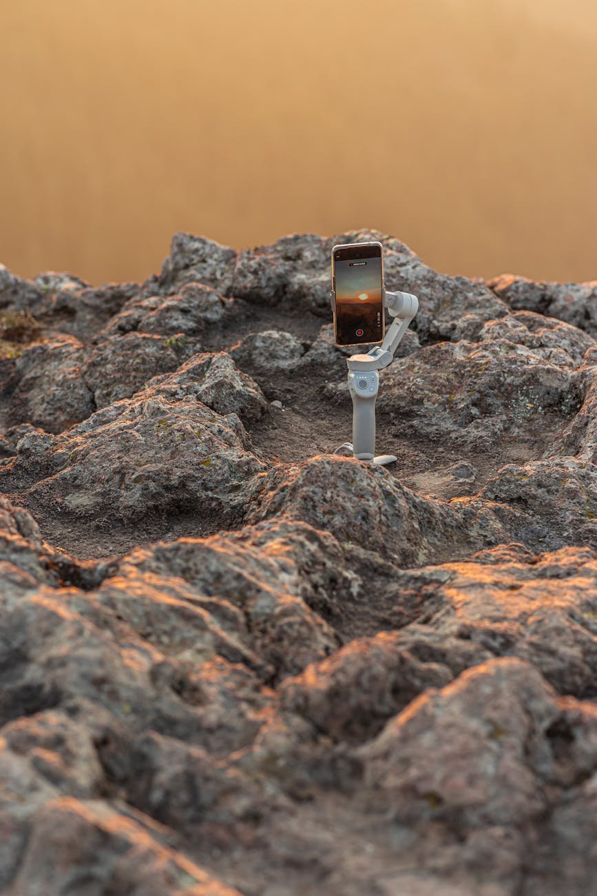 a smartphone attached to a gimbal on a rocky surface
